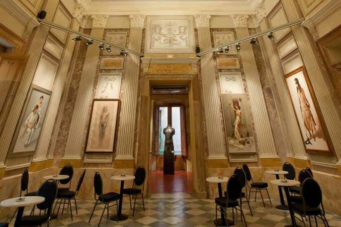 Sala elegante con mesas para eventos y arte clásico colgado en las paredes