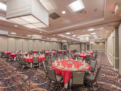 Sala de banquetes preparada para evento con mesas redondas y mantelería roja