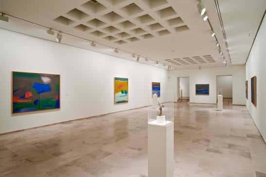 Interior de una sala de exposiciones con obras de arte abstracto en las paredes