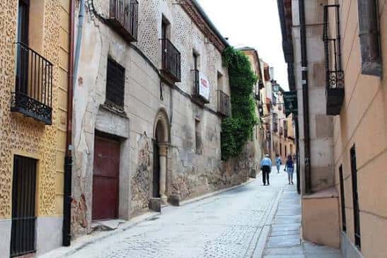 Calle empedrada del barrio con edificios históricos y personas caminando