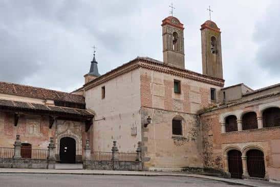 Fachada exterior del monasterio con torres campanario bajo cielo nublado
