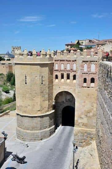 Vista panorámica de la Puerta del Alcázar y la Muralla de Segovia bajo un cielo azul