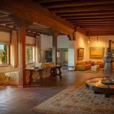 Interior del salón principal con vigas de madera, suelo de baldosa y decoración tradicional
