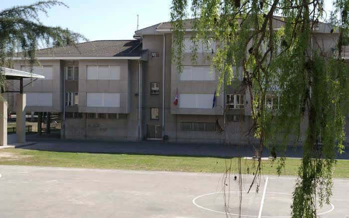 Fachada principal del Colegio Público Luis del Olmo con patio deportivo y banderas