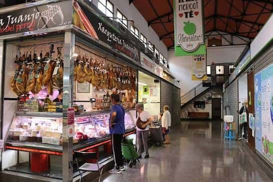 Interior del mercado mostrando puestos de productos y clientes