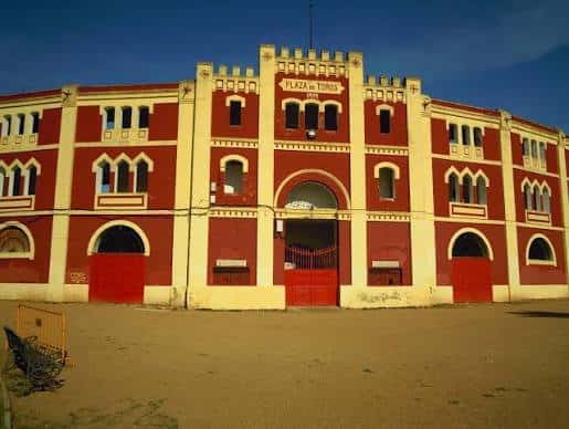 Vista frontal de la Plaza de Toros de Mérida mostrando su fachada roja y blanca con arcos