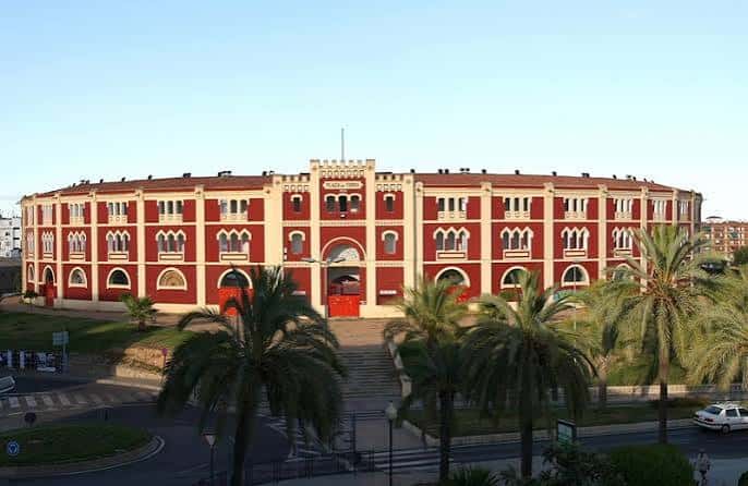 Plaza de toros de Mérida rodeada de palmeras bajo un cielo despejado