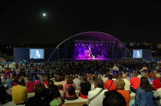 Concierto nocturno en el Anfiteatro de la Expo con escenario iluminado y gran afluencia de público