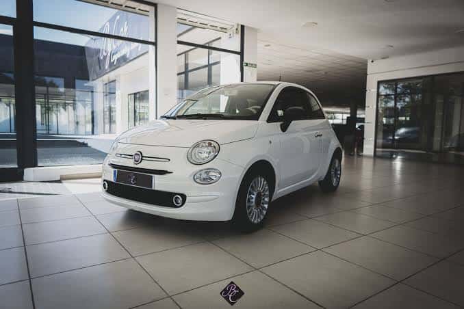 Interior del showroom mostrando un Fiat 500 blanco sobre suelo de baldosas