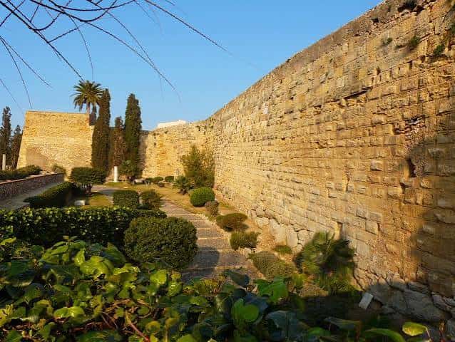 Vista lateral de la muralla romana con sendero y jardines bien cuidados