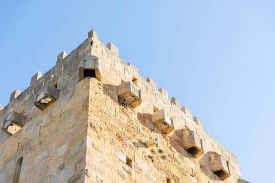 Detalle arquitectónico de una torre de la muralla con almenas y cielo despejado