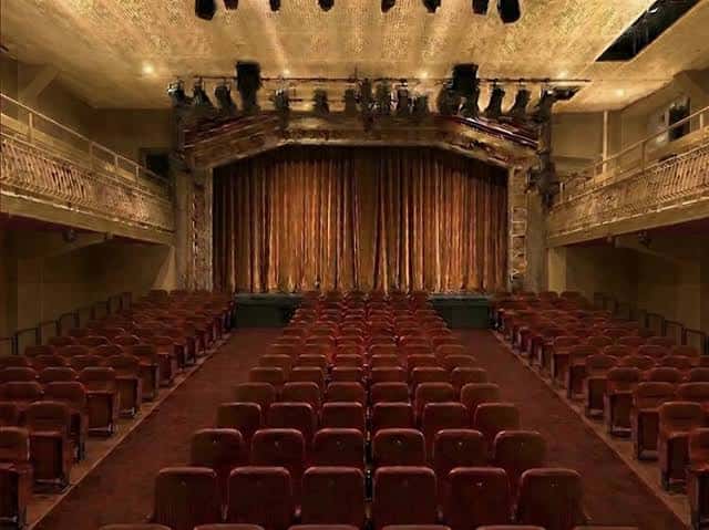 Interior del auditorio principal con butacas rojas y cortina dorada