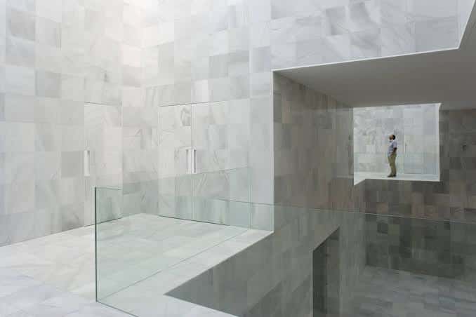 Interior del hall principal con paredes y suelo en mármol blanco y barandillas de cristal