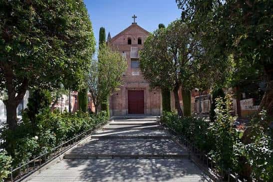 Acceso principal a la ermita rodeado de jardines y árboles, ideal para eventos al aire libre
