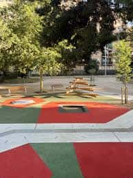 Zona de juego con elementos de madera y suelo colorido en el jardín