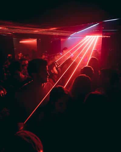 Pista de baile llena de gente bajo haces de luz láser rojos