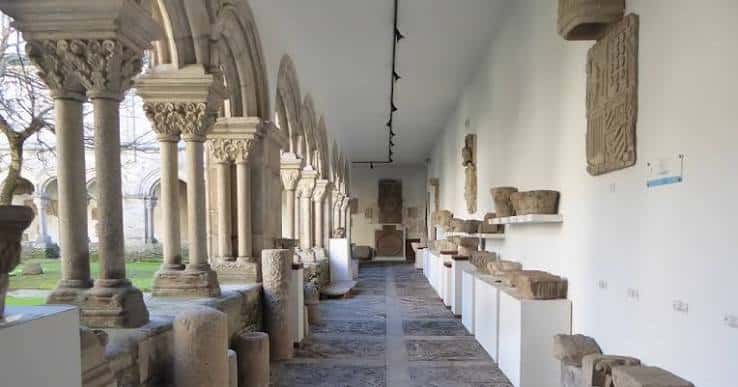 Claustro del Museo Provincial de Lugo con arcos románicos y exposición de piezas arqueológicas