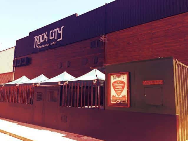 Vista exterior del local Rock City con su fachada de madera y toldos blancos