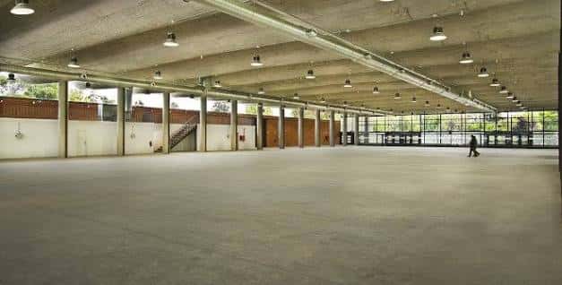 Interior amplio del pabellón con estructura de hormigón y suelo diáfano