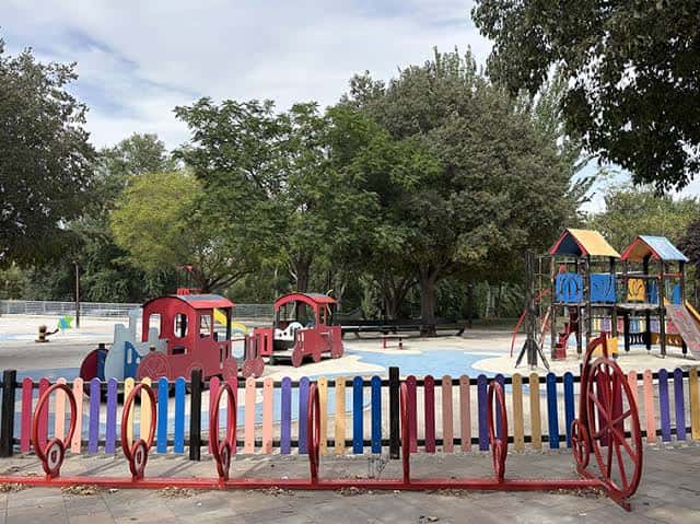 Zona de juegos infantiles con estructuras coloridas y cercado decorativo