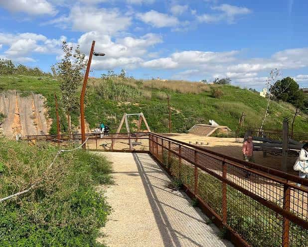 Paseo peatonal con barandilla metálica que conecta diferentes niveles del parque