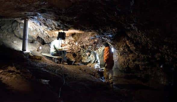 Vista interior de la Cueva del Conejar con arqueólogos trabajando en excavación