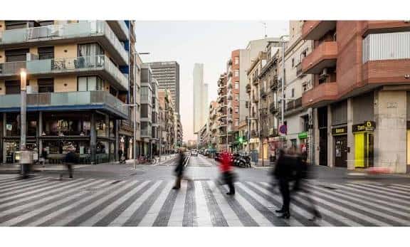 Vista de la calle Pere IV con el Torre Glòries al fondo y peatones cruzando