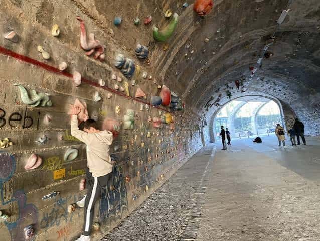 Escaladores en un túnel rocoso con agarres coloridos