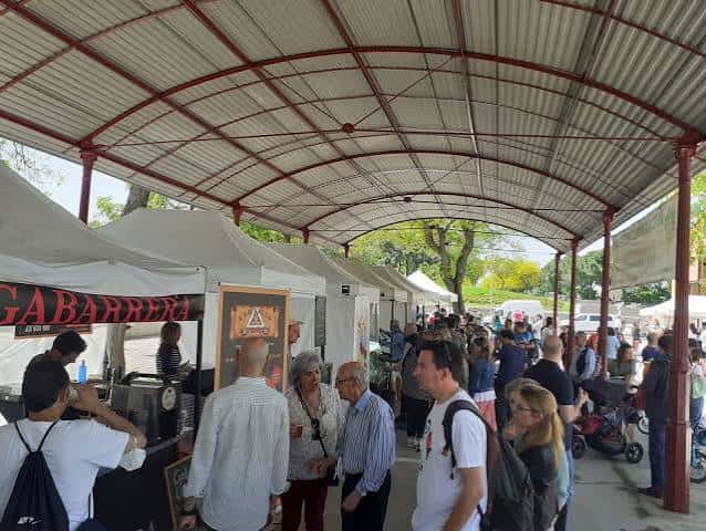 Vista interior del mercado con puestos bajo techo y público asistiendo