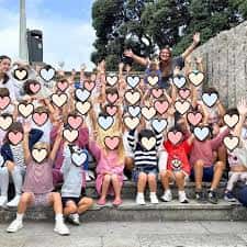 Grupo de niños y adultos celebrando en exteriores frente a la academia