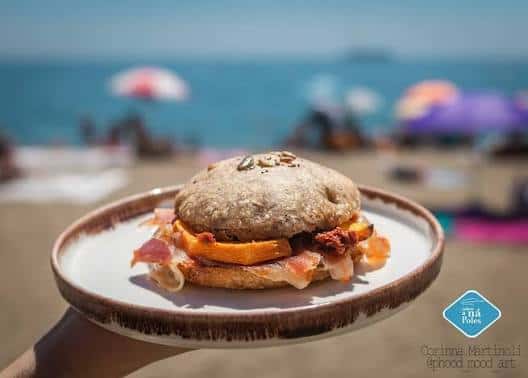 Plato de comida gourmet presentado al aire libre con fondo de playa desenfocado