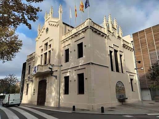 Fachada del edificio histórico junto a la plaza, con banderas y arquitectura modernista