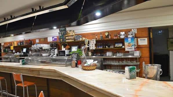 Interior de la cafetería Dendaraba mostrando barra y estanterías con productos