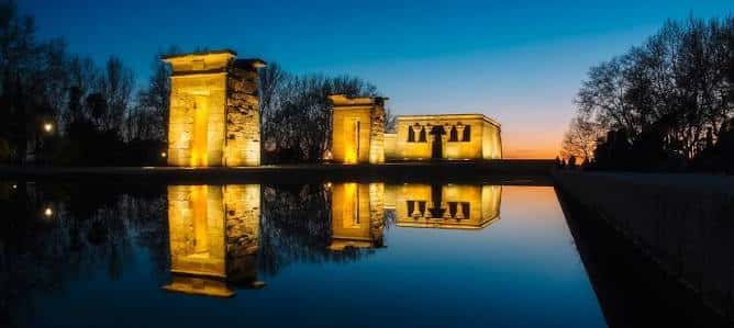 Templo de Debod iluminado al atardecer con reflejo en el agua