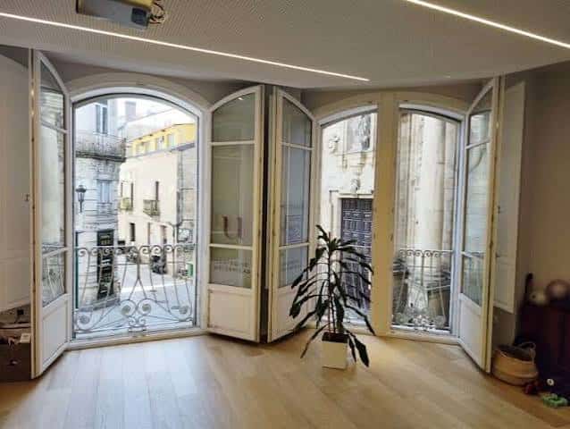 Sala de espera luminosa con grandes ventanales abertos y decoración minimalista