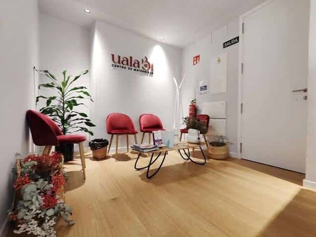Recepción del centro con sillas rojas, plantas y logotipo en la pared