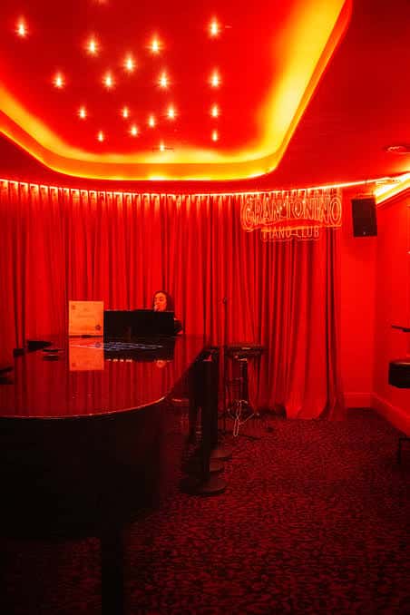 Escenario principal con cortinas rojas y piano bajo iluminación cálida