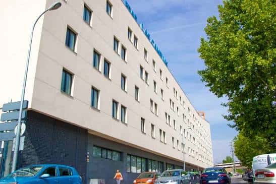 Fachada lateral del edificio del centro municipal de mayores con árboles y vehículos en primer plano