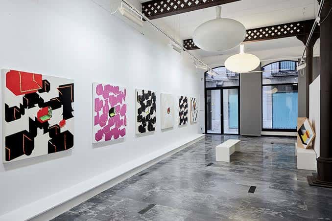 Vista del salón principal de la galería con iluminación moderna y exposiciones
