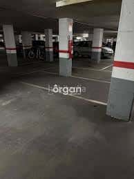 Interior del aparcamiento subterráneo con columnas y vehículos estacionados