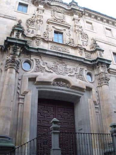Fachada ornamental de entrada con detalles escultóricos y puerta de madera tallada