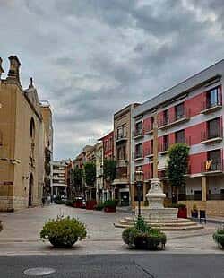Vista panorámica de la Plaça de la Puríssima Sang con su fuente central y edificios históricos bajo cielo nublado
