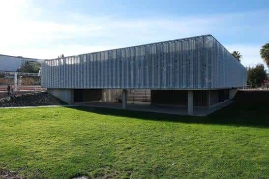 Vista exterior de la Biblioteca Clara Campoamor con fachada metálica y césped