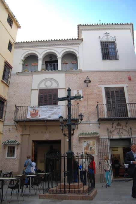 Vista exterior del edificio con cruz y personas en la entrada