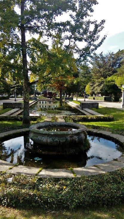 Fuente ornamental en el centro de la plaza rodeada de árboles