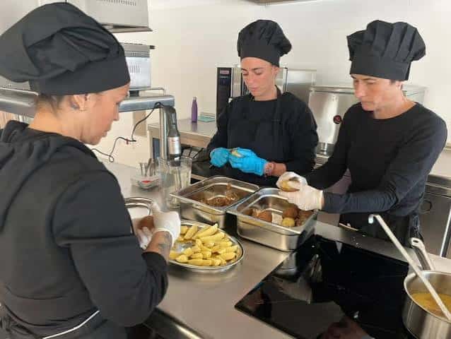 Estudiantes preparando alimentos en estación de trabajo de hostelería