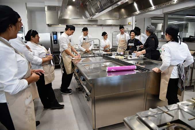 Clase práctica en cocina profesional con estudiantes y chef instructor