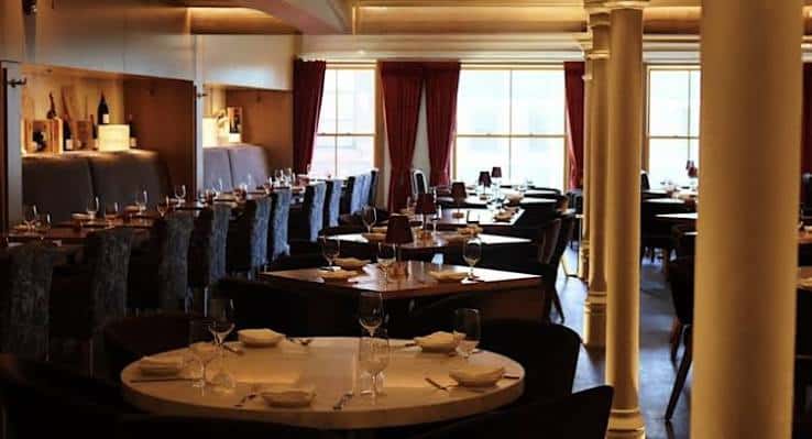 Interior elegante del restaurante con mesas dispuestas para cena y columnas decorativas