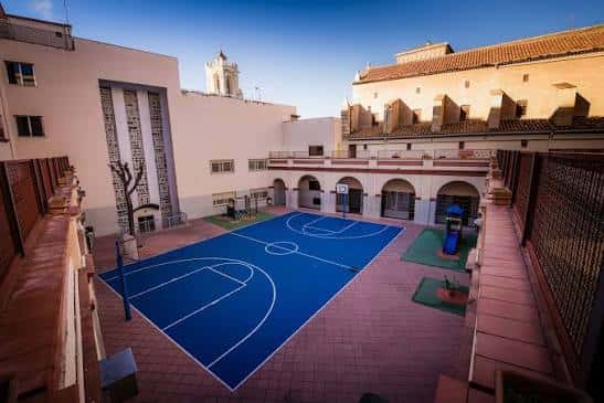 Patio interior con cancha de baloncesto azul rodeado de edificios escolares