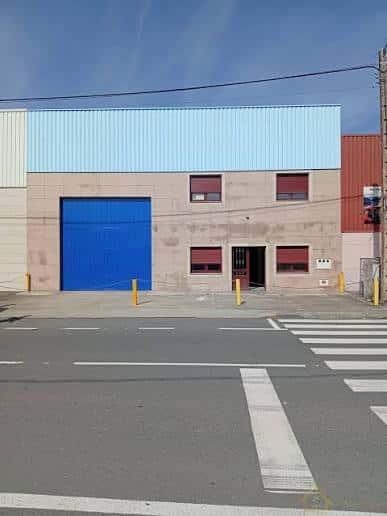 Vista exterior de la nave industrial con puerta azul y fachada moderna